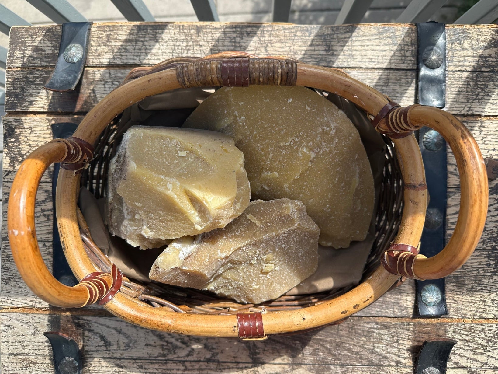 A wicker basket on wooden table full of large chunks of raw beeswax 